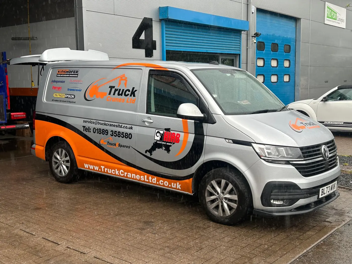 Branded Truck Cranes service vehicle outside a workshop